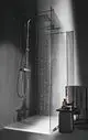 Duschbereich mit klaren Glaswänden, Regenbrause und Handbrause. Neben der Dusche steht ein kleiner Ablagetisch mit Pflegeprodukten. Ideal Standard Duschsystem.